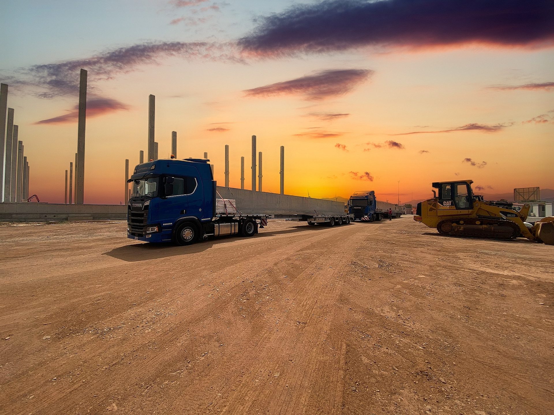 Convoglio di mezzi Pittorra al tramonto su un cantiere con travi in calcestruzzo